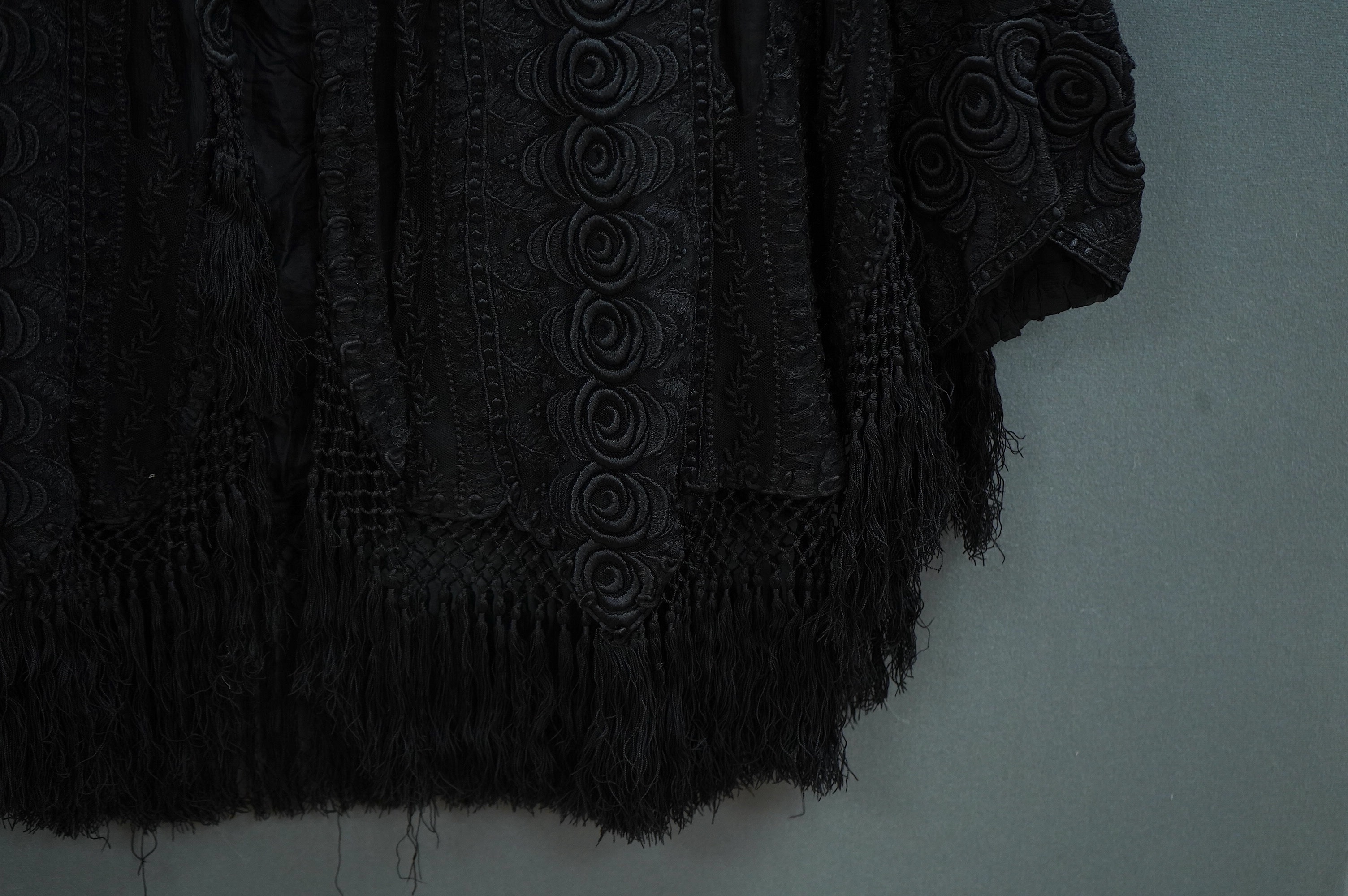 An Edwardian black chiffon and lace evening jacket with tassel decoration to the front and back, edged with tasselled fringing to the edge of sleeves and bottom, 85cm long from nape of neck at the back to bottom of tasse